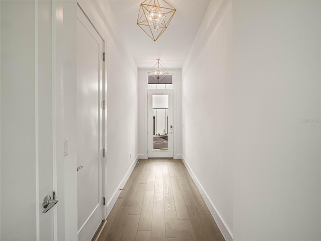 hallway with hardwood / wood-style flooring and a notable chandelier