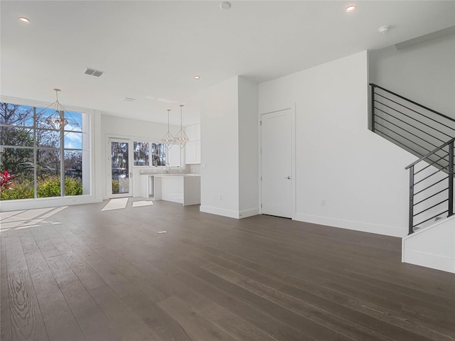 unfurnished living room with a chandelier and dark hardwood / wood-style floors