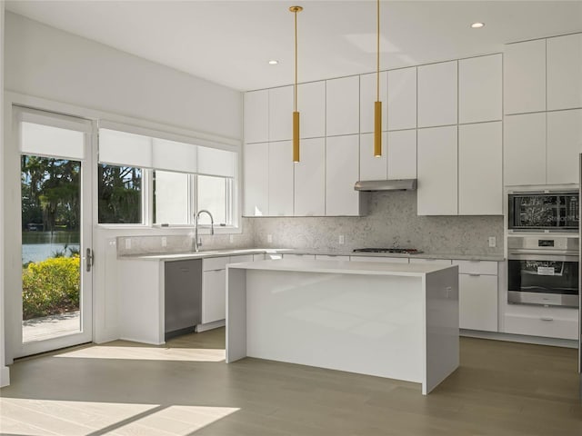 kitchen featuring a kitchen island, white cabinetry, a healthy amount of sunlight, and appliances with stainless steel finishes