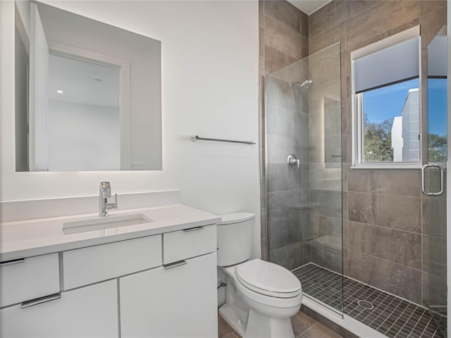 bathroom with tile patterned floors, vanity, toilet, and a shower with door