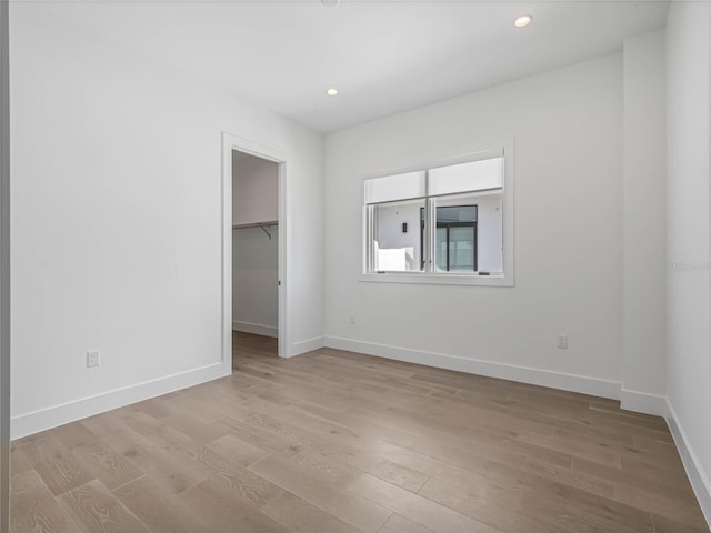 unfurnished bedroom featuring a closet, a spacious closet, and light hardwood / wood-style flooring