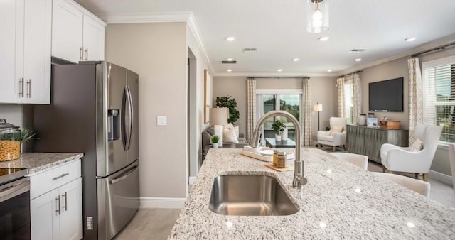 kitchen with light stone counters, white cabinetry, and sink