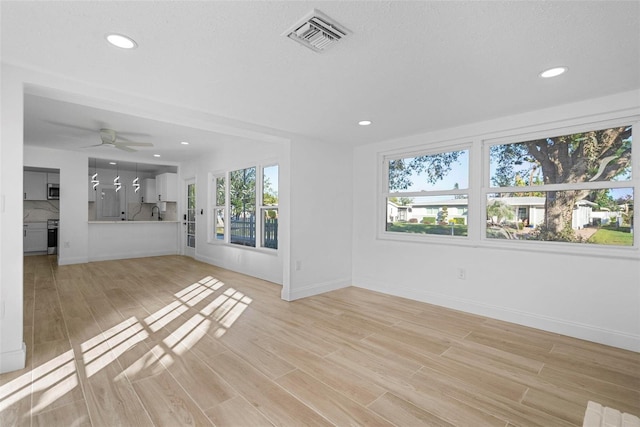 unfurnished living room featuring ceiling fan and light hardwood / wood-style flooring