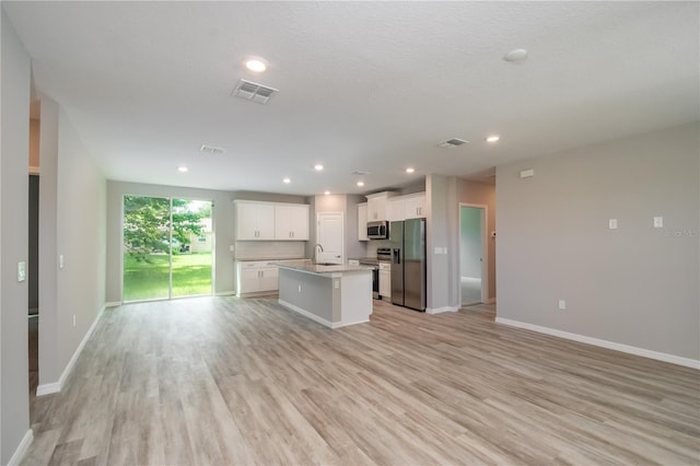 kitchen with stainless steel appliances, a kitchen island with sink, sink, white cabinets, and light hardwood / wood-style floors