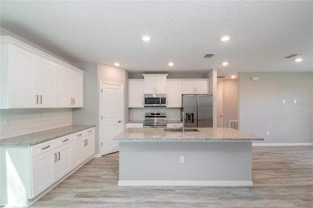 kitchen with white cabinets, appliances with stainless steel finishes, and a kitchen island with sink