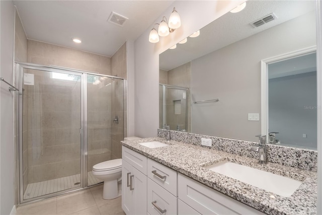 bathroom featuring tile patterned flooring, vanity, toilet, and a shower with shower door