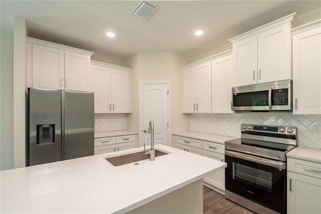 kitchen with stainless steel appliances, light countertops, visible vents, white cabinetry, and a sink