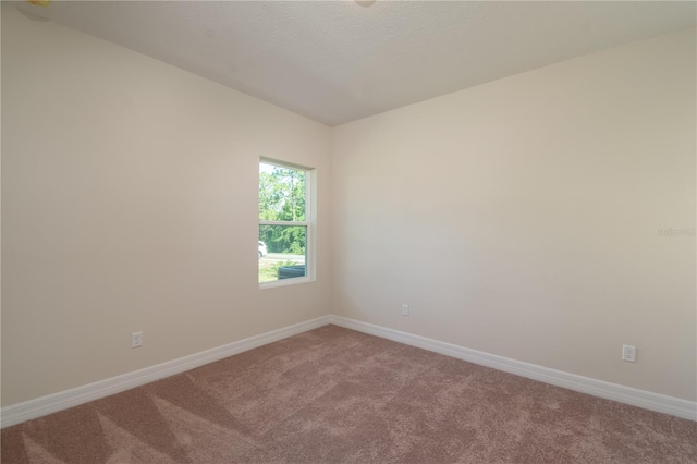 empty room with carpet flooring, a textured ceiling, and baseboards