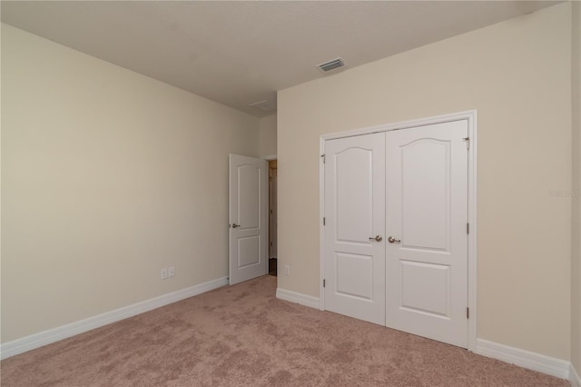 unfurnished bedroom featuring baseboards, a closet, visible vents, and light colored carpet