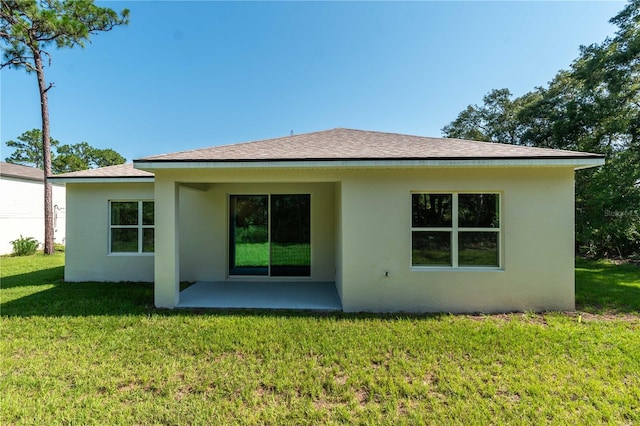 back of house featuring stucco siding, a shingled roof, a patio, and a yard