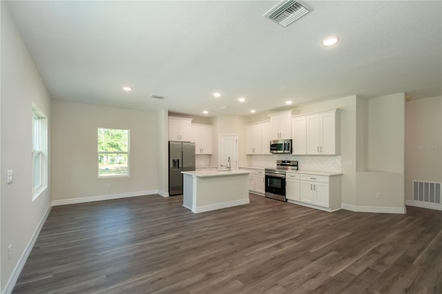 kitchen featuring stainless steel appliances, visible vents, white cabinets, open floor plan, and light countertops