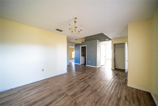 unfurnished room featuring dark wood-type flooring and a notable chandelier