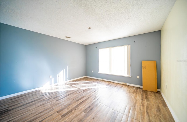 unfurnished room featuring hardwood / wood-style floors and a textured ceiling