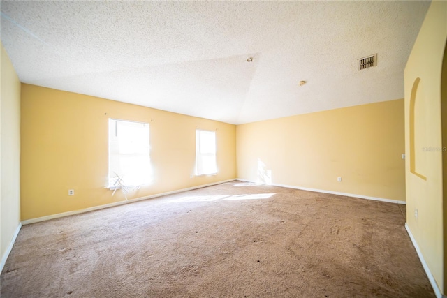 carpeted empty room featuring a textured ceiling and vaulted ceiling