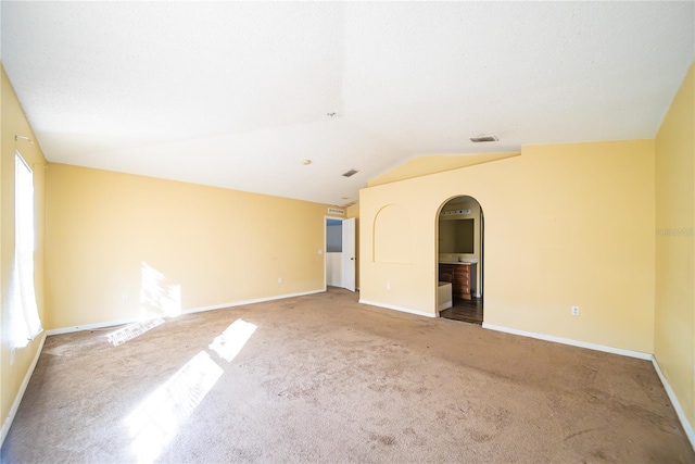 spare room with carpet floors and vaulted ceiling