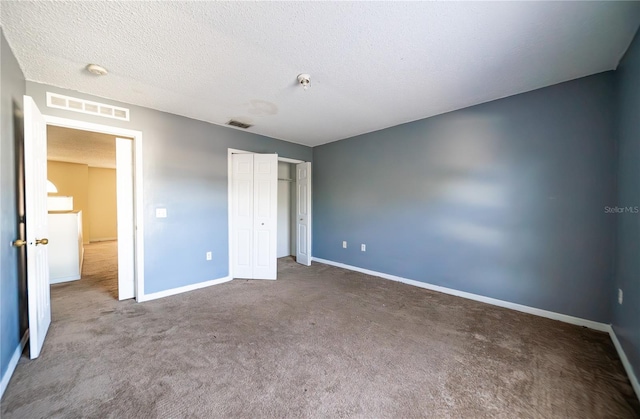 unfurnished bedroom with a closet, a textured ceiling, and dark colored carpet