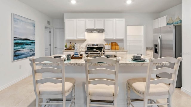 kitchen featuring white cabinets, a kitchen bar, stainless steel appliances, and a kitchen island with sink