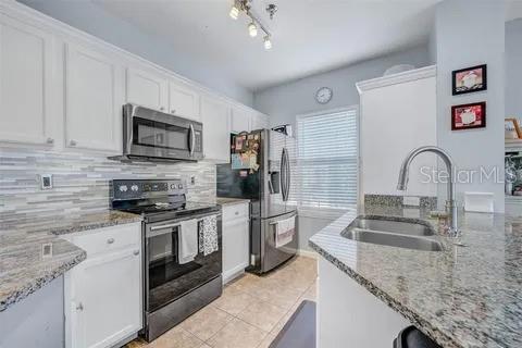 kitchen featuring white cabinets, stainless steel appliances, light stone counters, and sink