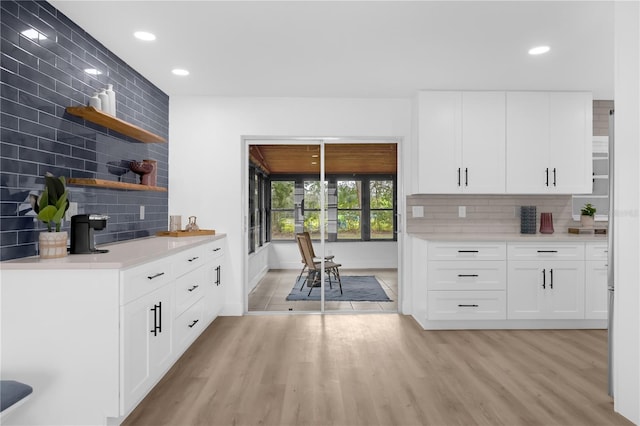 kitchen featuring backsplash, light hardwood / wood-style flooring, and white cabinets