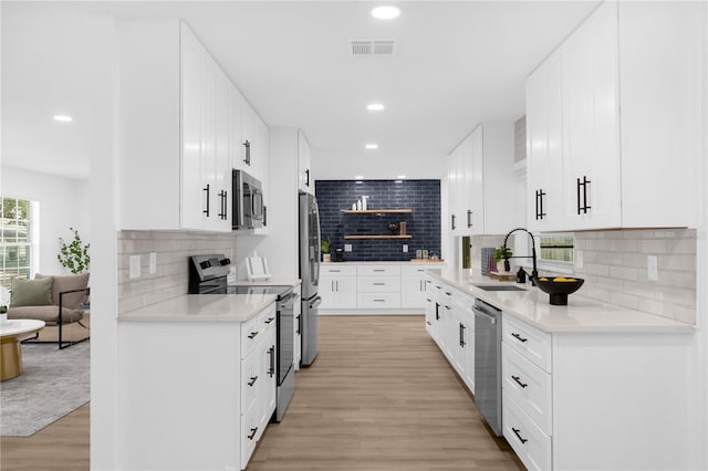 kitchen with tasteful backsplash, white cabinetry, sink, and stainless steel appliances