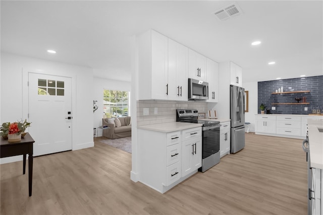 kitchen with tasteful backsplash, white cabinetry, light hardwood / wood-style flooring, and stainless steel appliances