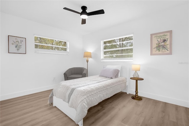 bedroom featuring ceiling fan, light hardwood / wood-style flooring, and multiple windows