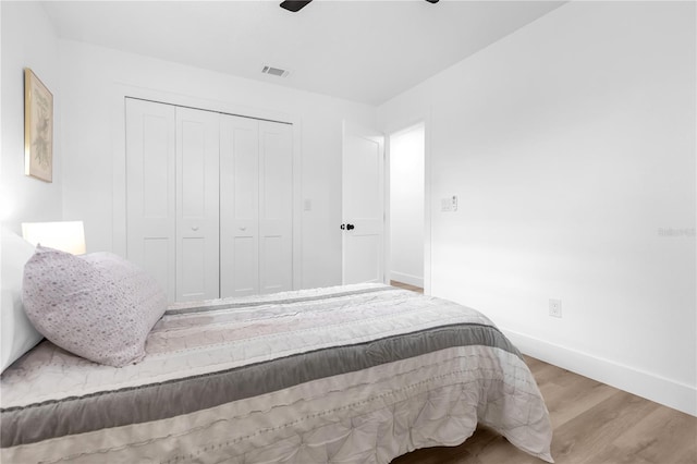 bedroom with ceiling fan, a closet, and wood-type flooring