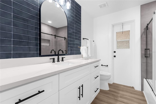 full bathroom with vanity, hardwood / wood-style flooring, toilet, and enclosed tub / shower combo