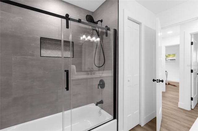 bathroom with wood-type flooring and shower / bath combination with glass door