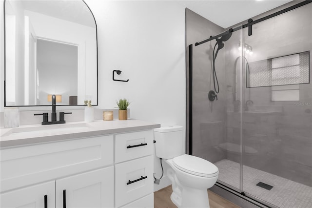 bathroom featuring hardwood / wood-style flooring, vanity, toilet, and a shower with door