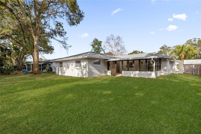 back of house featuring a sunroom and a lawn