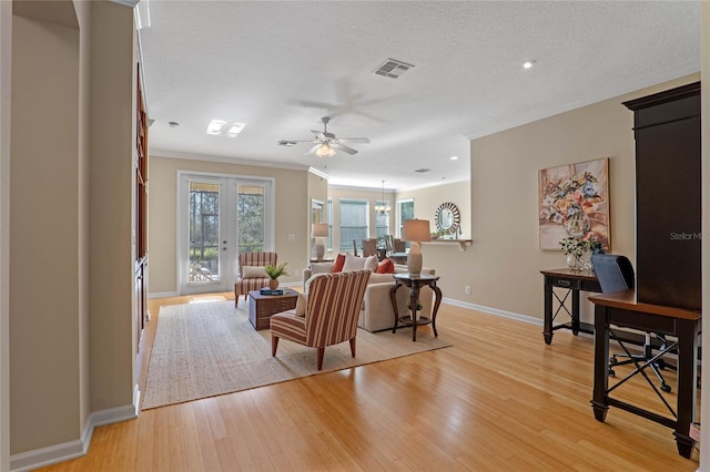 living room featuring crown molding, french doors, ceiling fan with notable chandelier, and light wood-type flooring