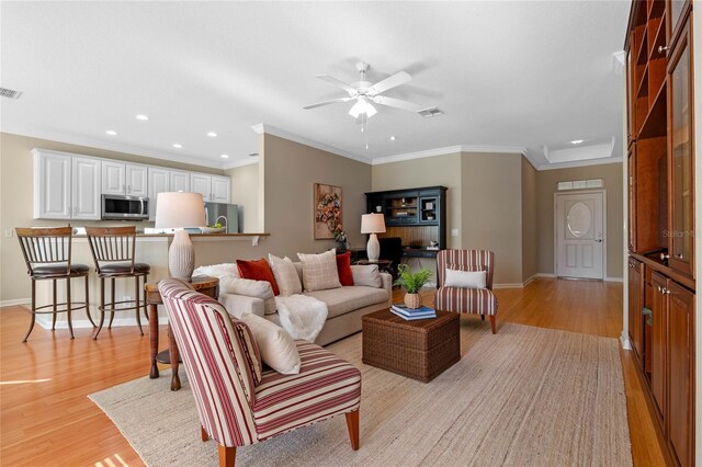 living room with ceiling fan, light hardwood / wood-style flooring, and ornamental molding