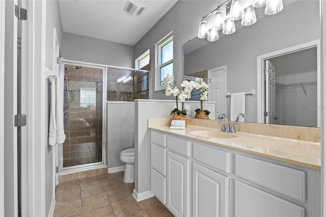 bathroom with tile patterned flooring, vanity, an enclosed shower, and toilet