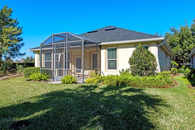 back of house with a yard and glass enclosure