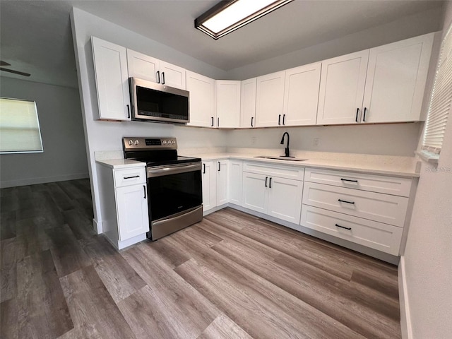 kitchen with hardwood / wood-style flooring, sink, white cabinets, and appliances with stainless steel finishes