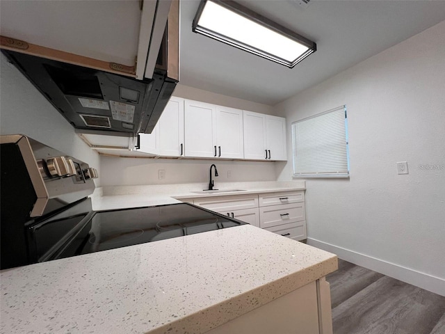 kitchen with white cabinets, stove, wood-type flooring, and sink