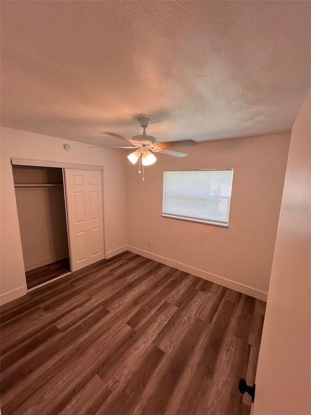 unfurnished bedroom with ceiling fan, dark hardwood / wood-style flooring, a textured ceiling, and a closet