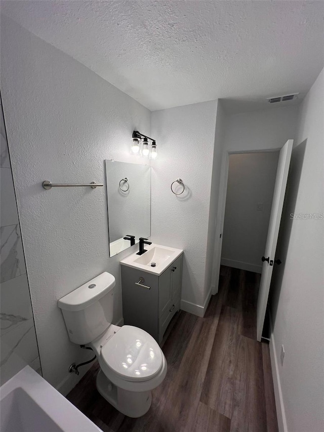 bathroom featuring vanity, hardwood / wood-style flooring, toilet, a textured ceiling, and walk in shower