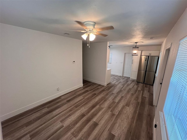 unfurnished living room with a textured ceiling, ceiling fan, and dark wood-type flooring