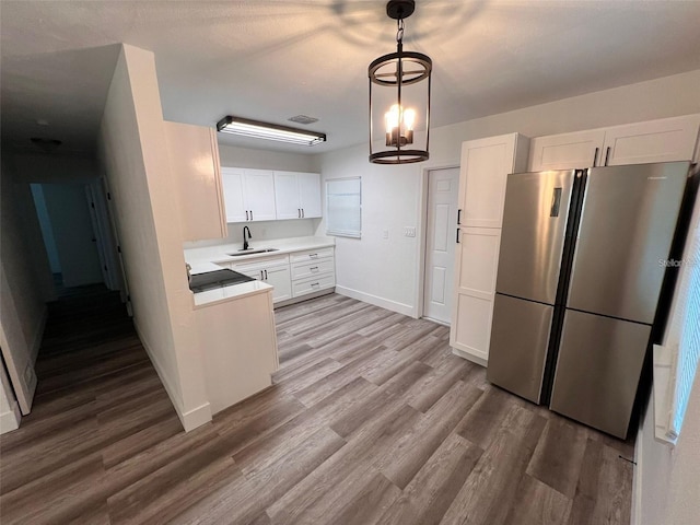 kitchen with stainless steel refrigerator, sink, white cabinets, and an inviting chandelier