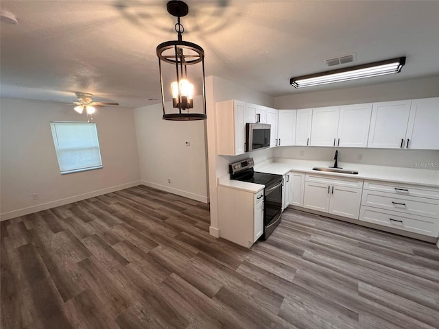 kitchen with electric range, decorative light fixtures, white cabinetry, and sink