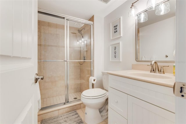 bathroom featuring tile patterned floors, vanity, a shower with shower door, and toilet