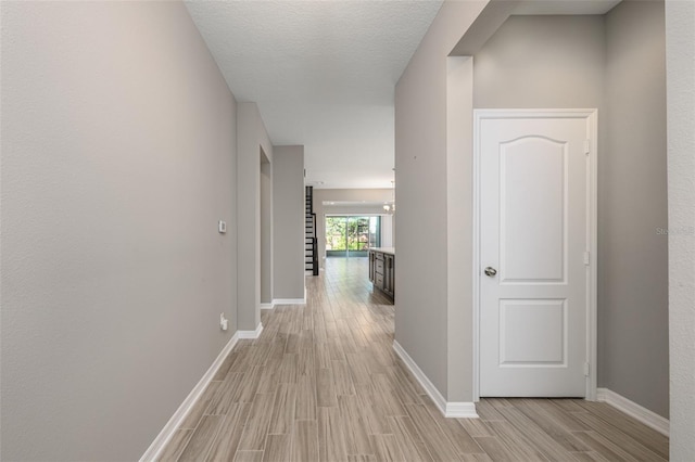 hall with a textured ceiling and light wood-type flooring