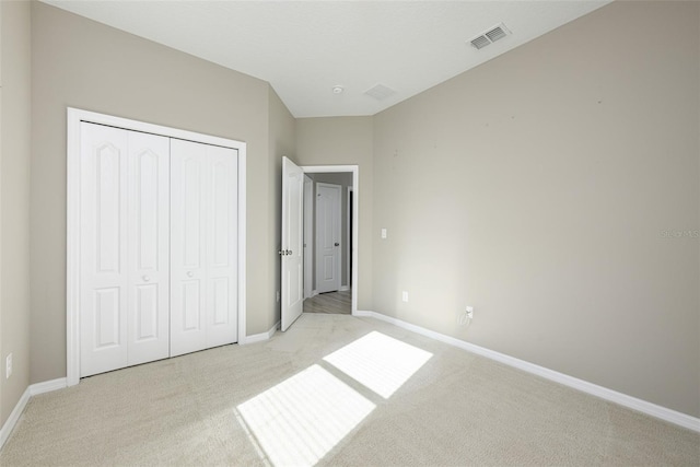 unfurnished bedroom featuring light colored carpet and a closet