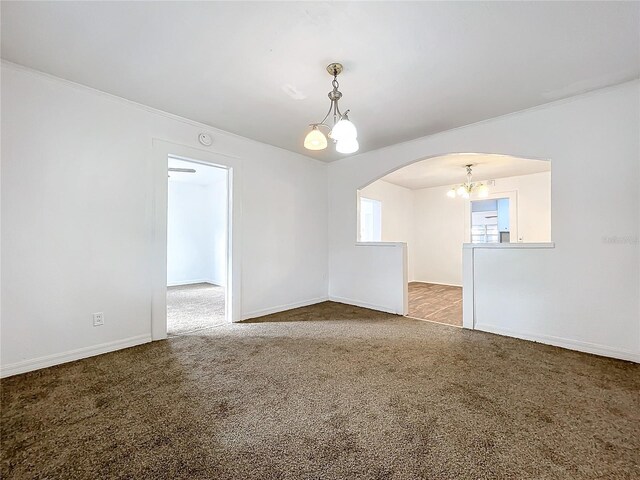 carpeted spare room featuring ornamental molding and an inviting chandelier