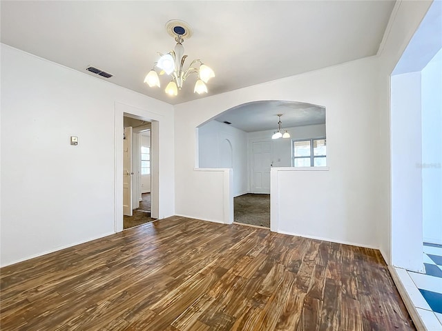 empty room with crown molding, dark hardwood / wood-style floors, and a chandelier