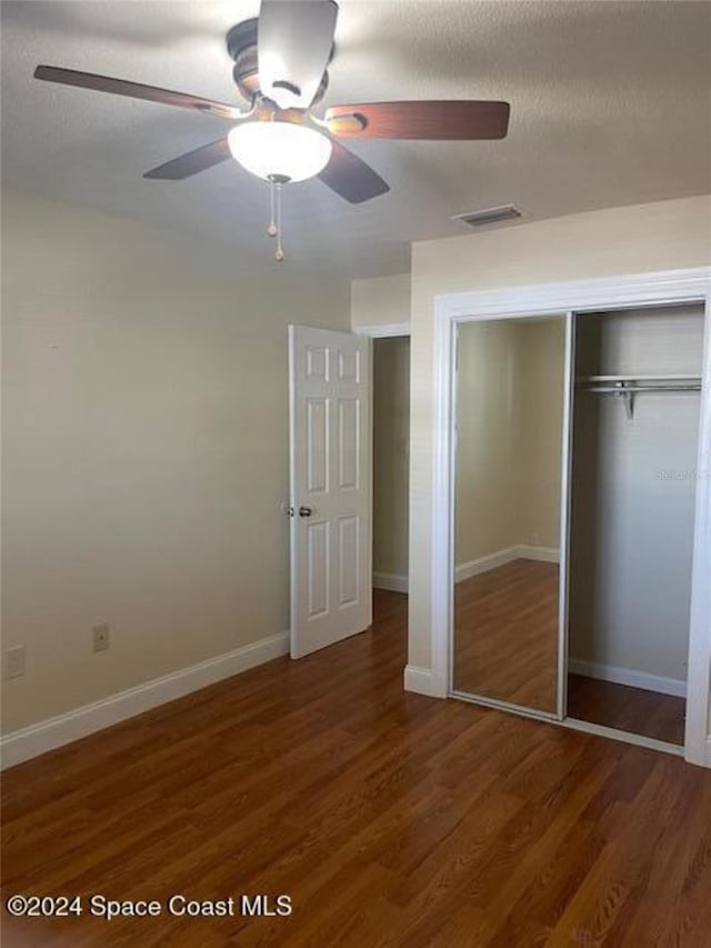 unfurnished bedroom featuring a textured ceiling, ceiling fan, a closet, and dark hardwood / wood-style floors