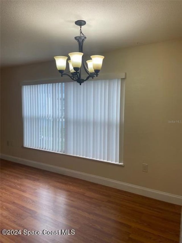 spare room featuring dark wood-type flooring and a notable chandelier