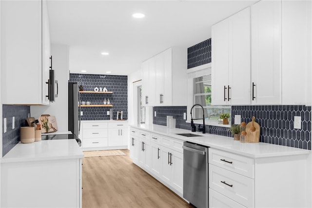 kitchen with sink, backsplash, appliances with stainless steel finishes, white cabinets, and light wood-type flooring